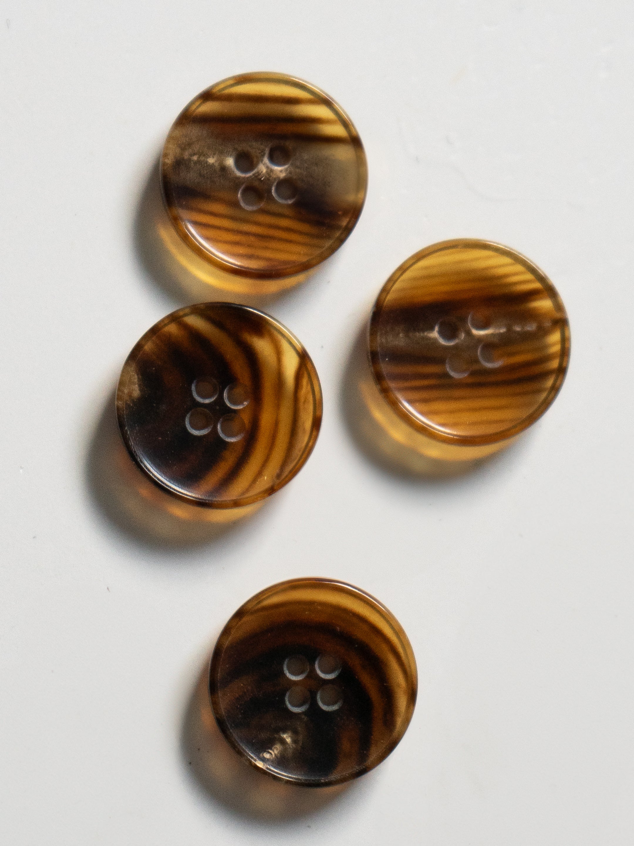 A set of round brown cardigan buttons with a 4-hole design, arranged on a white background.